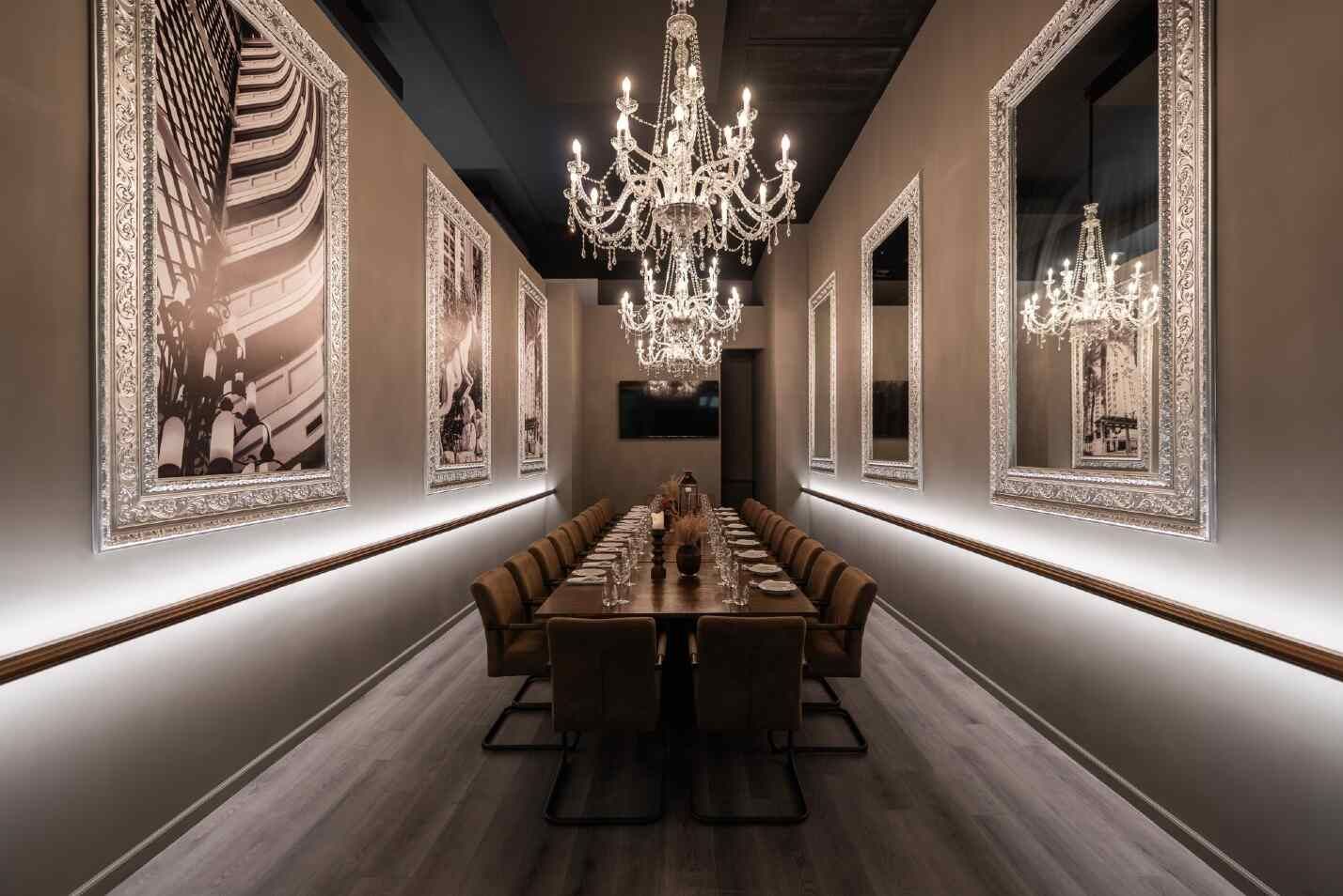 חדר פרטי יוקרתי עם שולחן ארוך מעליו משתלשלות נברשות קריסטל